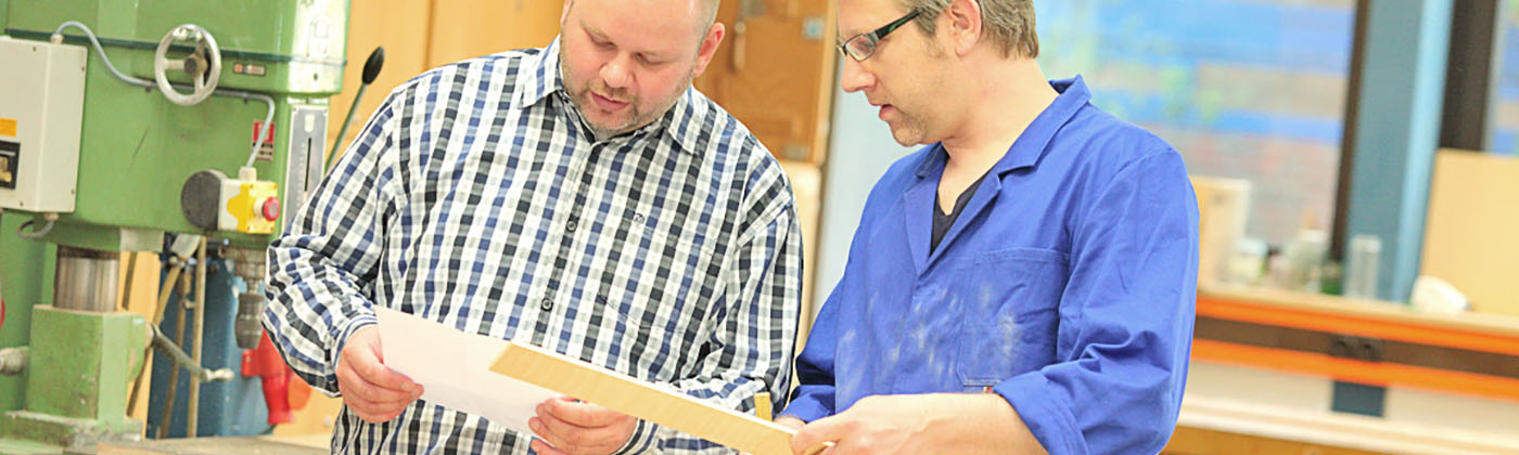 Berufsförderungswerk Umschulung berufliche Rehabilitation Arbeitspädagoge in der Ausbildung Ein Ausbilder in der Umschulung der Arbeitspädagogen am Berufsförderungswerk erklärt einem Rehabilitanden die Planskizze zu einer Aufgabe.