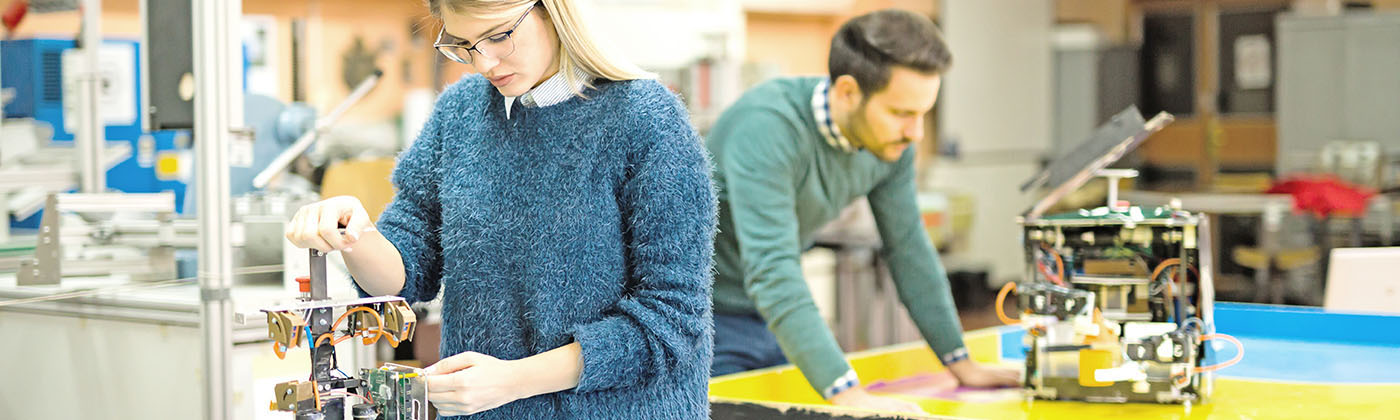 Berufsförderungswerk Umschulung berufliche Rehabilitation Frau und Mann beim Programmieren von Robotern Berufsförderungswerk Umschulung berufliche Rehabilitation Frau und Mann beim Programmieren von Robotern